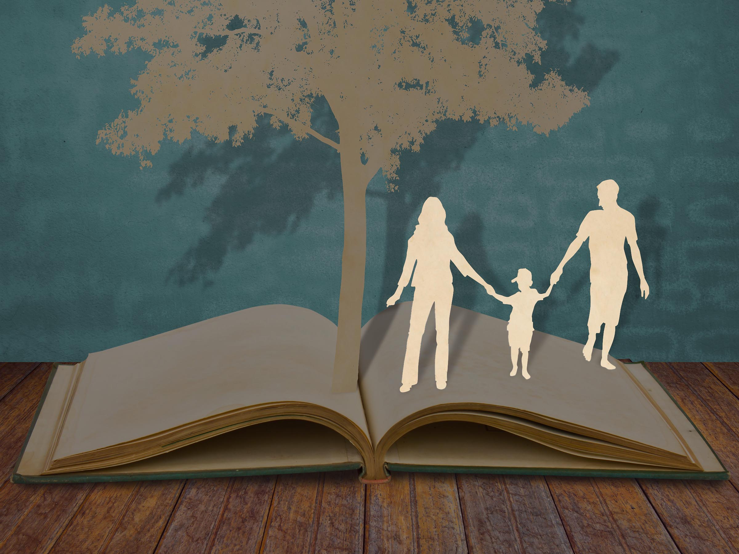 Family cut out of paper holding hands walking across an open book