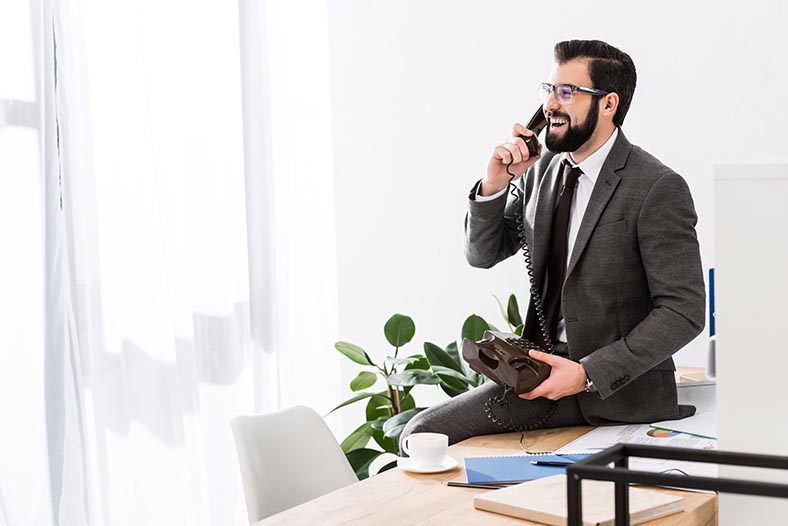 Image of man on the phone sitting on his desk